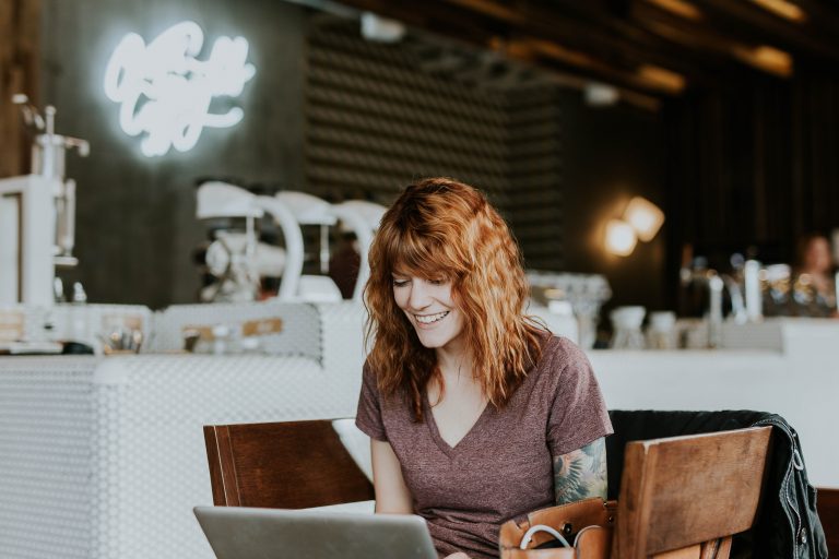 red headed woman at a coffee shop on a laptop