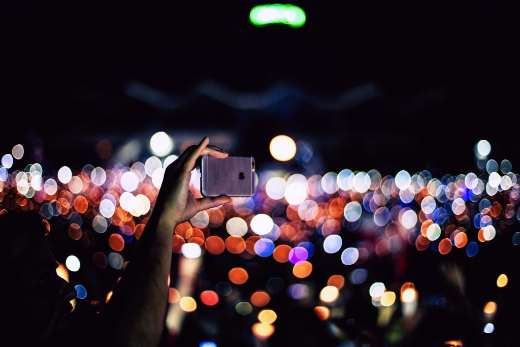 Hand holding phone above crowd at a concert